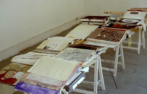 A long row of trestle tables covered with open books.