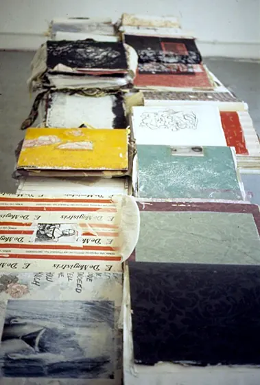 Stacks of handmade books in colourful covers on a table, seen from above.