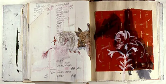 An open book with a red page holding a white flower drawing.