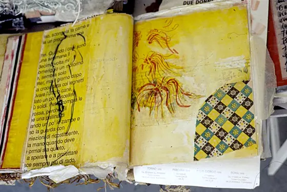 An open yellow book with black line drawings and a patch of patterned fabric.