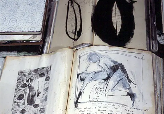 An open book with a black ink figure drawing beside floral paper.