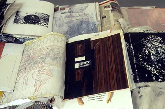 An open book with pages of pencil drawing and dark wood-grain paper.