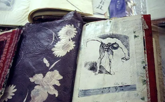 An open book with navy fabric printed with white flowers beside a page of drawing.