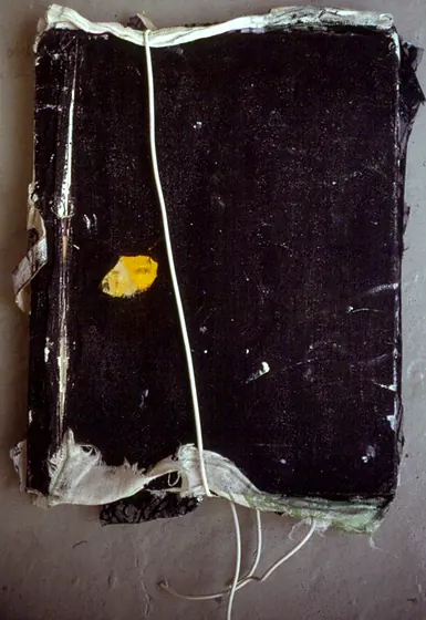A black book bound with white cord, with a small yellow patch.