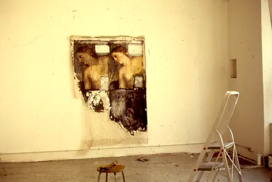 Construction Installation 8: the torn painting with two female heads on a wall, with a stepladder and a stool in front.